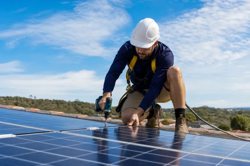 Installateur fixant un panneau solaire sur un toit