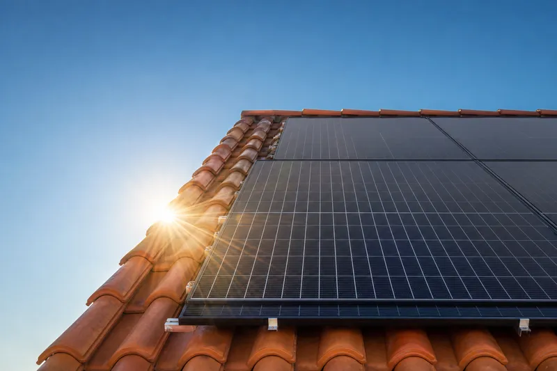 Panneaux solaires sur un toit en tuiles face au soleil